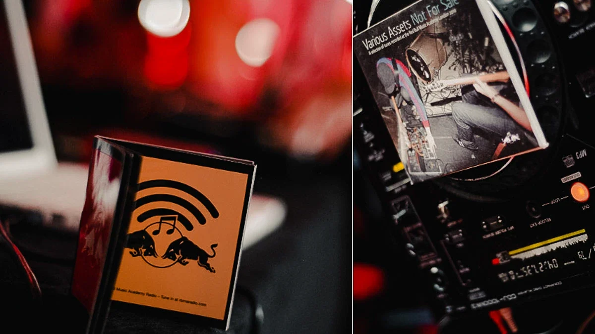 A DJ booth at the Red Bull Music Academy with a CD sleeve and an Academy Radio booklet, lit against red bokeh